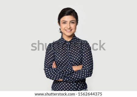 Portrait beautiful smiling Indian girl with arms crossed standing isolated on grey studio background, pretty young woman with healthy toothy smile looking at camera, satisfied client customer Royalty-Free Stock Photo #1562644375