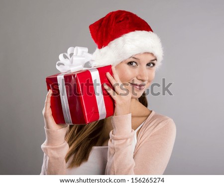 Beautiful christmas woman is holding red gift in studio