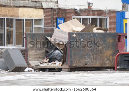 dumpster is being filled with trash after business has closed