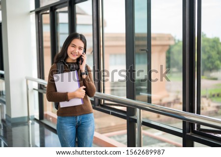 Long-haired female student holding a book and posing at the university