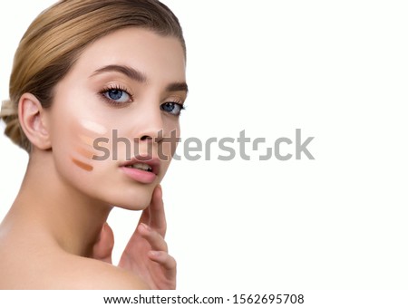 Young woman applying 4 color samples of facial foundation cream or corrector at her face. Beauty model with perfect fresh skin and long eyelashes. Makeup Concept. Royalty-Free Stock Photo #1562695708