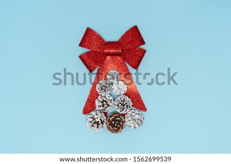 2020 New year composition. Stylish decor concept, Christmas tree made of fir cones with big red bow on blue backdrop. Flat lay, top view, copy space. Background for postcard, for desktop