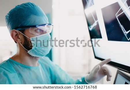 Doctor surgeon examines an x-ray picture on a monitor in the office.