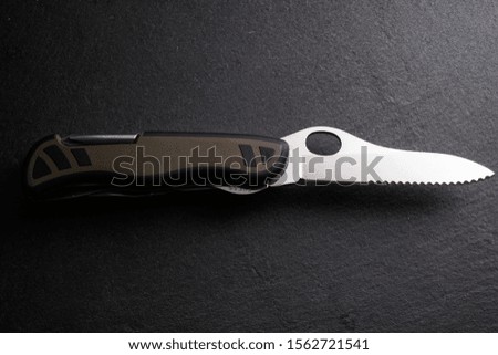 Multipurpose survivor tool knife on dark slate stone background