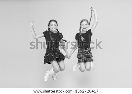 Join celebration. Kids girl wear checkered dresses. National holiday. School uniform. Scottish style. Cheerful friends schoolgirls jumping yellow background. Celebrate holiday. Scottish holiday.