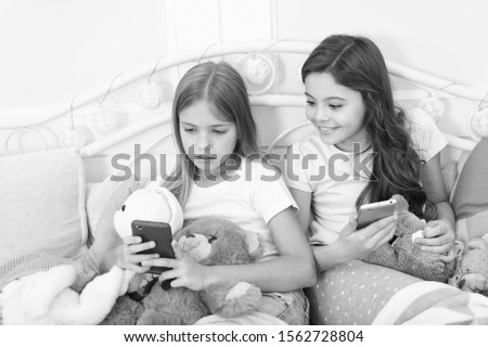 Well, you only look. Ordering gifts for Christmas and New Year by phone. Little girls use smartphone in bed. Happy little children with mobile phone. Merry Christmas and Happy New Year greetings.