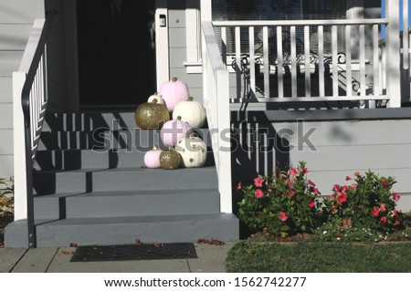 Pink, gold and white pumpkins on the front steps of a home in Monterey, CA are a cute fall display.
