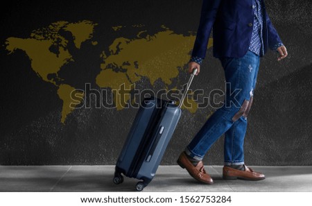 Travel Concept. Young Person with Luggage Walking by the Wall. World Map as background