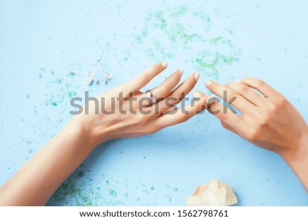 woman hand with sea shell manicured on blue background, spa concept