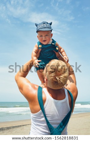 Young father tossing up high to air little  happy baby boy on white sand sea beach. Outdoors healthy child activity, active lifestyle, having fun on family summer vacation with kids on tropical island