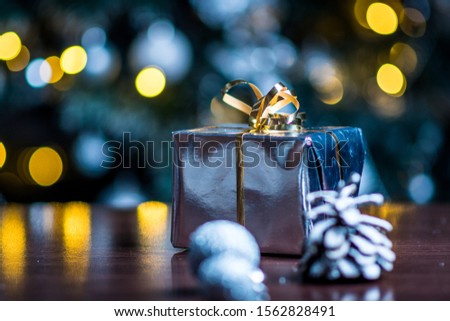 Christmas gifts in silver paper and silver bulbs on wood table
