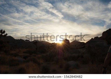 Looking at a mountain ridge in Joshua Tree National Park with the sun setting behind 