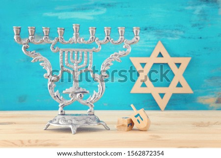 religion image of jewish holiday Hanukkah with menorah (traditional candelabra) and spinning top over wooden table and blue background