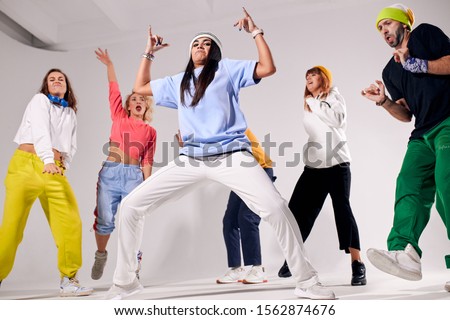 Cool teenagers spending great time on hip hop party, standing in full length, dancing with pleasure, isolated on white colour background, having fun with friends, low angle shot