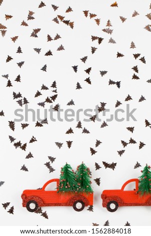Small toy cars carring christmas tree on white background . Sesonal holidays, greeting card, christmas mood concept. copy space close up