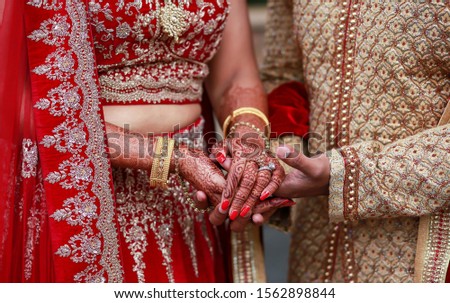 Indian Couple holding hands and bride showing mehndi design writh engagement rings