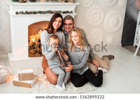 Happy family having fun together at Christmas eve near fireplace