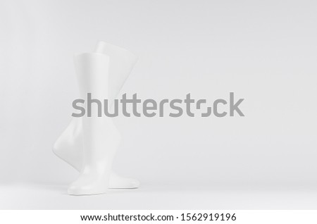 Abstract white modern statuette of two elegant white dancing legs on white background with copy space.