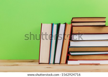 Simple Simple composition of many hardback books, unprocessed books on a wooden table and a green background. back to school. Copy space. Education.