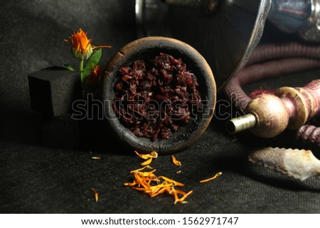 bowl with tobacco for hookah. calendula on a black background. smoking hookah