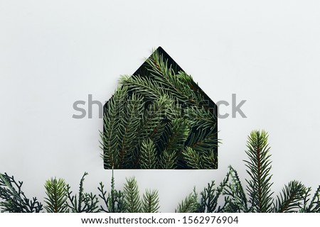Christmas minimal concept - simple house silhouette made of christmas tree branch. Flat lat, top view. Abstract christmas tree. Abstract nature background. Christmas concept. Simple shape.