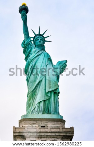 Photo close-up of the Statue of Liberty on a sunny day and blue sky with clouds. Liberty Island. NYC, USA.