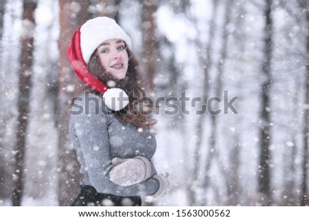 Girl in a winter park in the afternoon in snowfall
