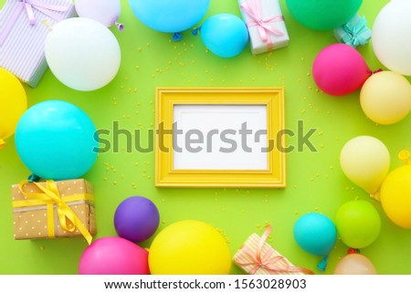 Composition with balloons, gifts and blank photo frame on color background
