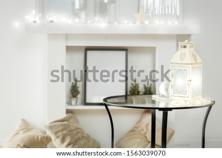 Round glass table with some winter ornaments and decoration with bright white fireplace wall background. Christmas time. Nice luxurious home interior.
