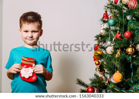cute five year old boy and sock for Christmas gifts on white background near Christmas tree