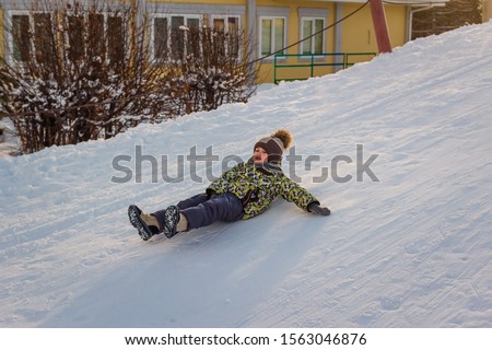 cheerful boy sledding in the winter, the boats with the mountains. winter fun