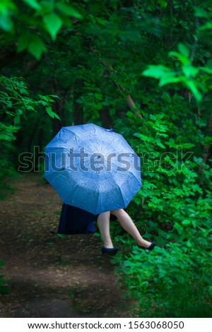 The concept of mystery. The girl hid behind a blue umbrella. Woman levitates.