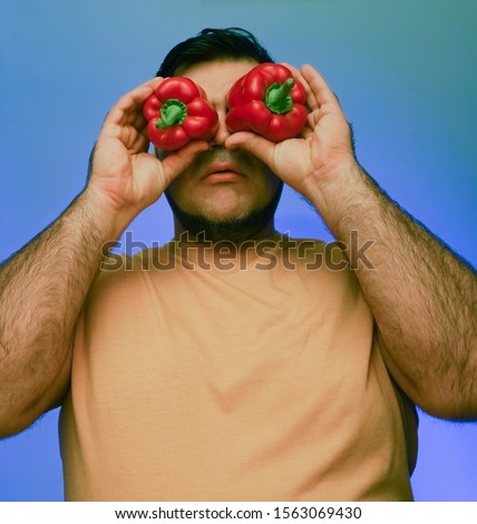 Funny picture of a man holding big papricas in front of her face. isolated on white or gray background. 