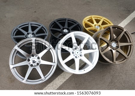 Alloy wheels of different colors, lie on the pavement