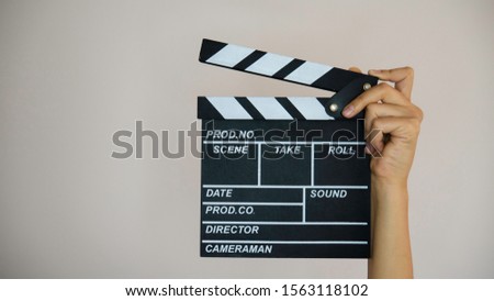 Female hand holding wooden movie clapper.