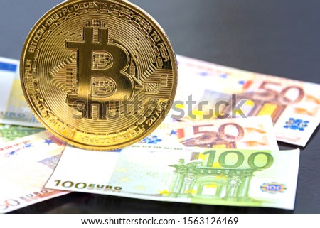 golden bitcoin (new virtual currency) on traditional euro. Euro banknotes as a background. Concept: mining and digital currencies.