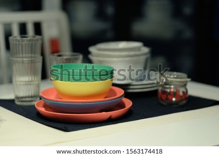 close up colorful bowls and plates on dining table. blurred dark background 