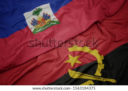 waving colorful flag of angola and national flag of haiti. macro