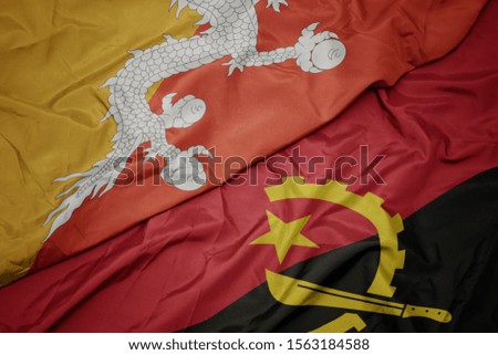 waving colorful flag of angola and national flag of bhutan. macro