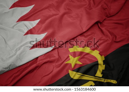 waving colorful flag of angola and national flag of bahrain. macro