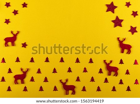 Christmas and New Year composition. Christmas silhouette of deer and fir-trees, red decorations on bright yellow background.  Flat lay with copy space. Top view