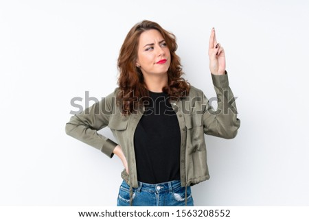 Young Russian woman over isolated white background with fingers crossing and wishing the best