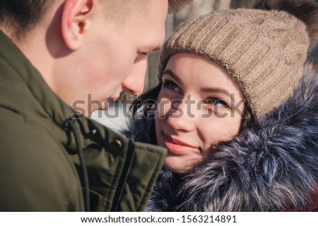 Loving young beautiful couple in the park on a bright sunny day. The girl looks into the eyes of her boyfriend and smiles