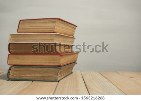 Old Books on a wooden table and white wall background. 