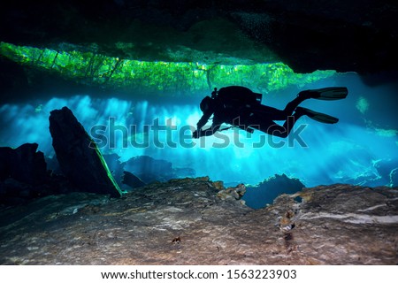 Cave Diver diving through the lights in a Cenote in Mexico Royalty-Free Stock Photo #1563223903