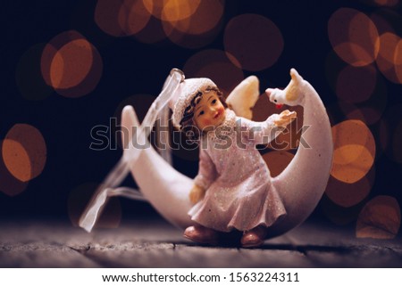 Sweet Vintage Angel Figurine in front of Blurry, Colorful Christmas Lights
