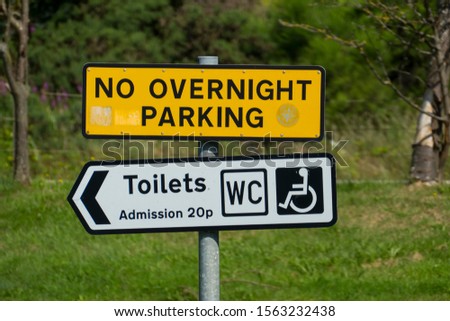 Sign on a public parking bay with the English text No overnight Parking, Toilets, Admission 20p, WC