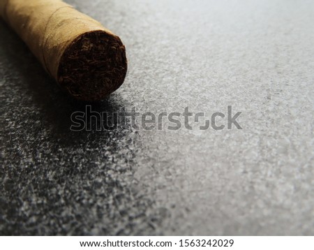 Brown rolled cigar on a black metal surface