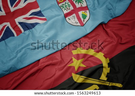 waving colorful flag of angola and national flag of Fiji . macro