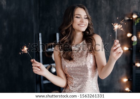 Fashion young beautiful woman in luxury dress and makeup. christmas and new year. girl with sparlight lights